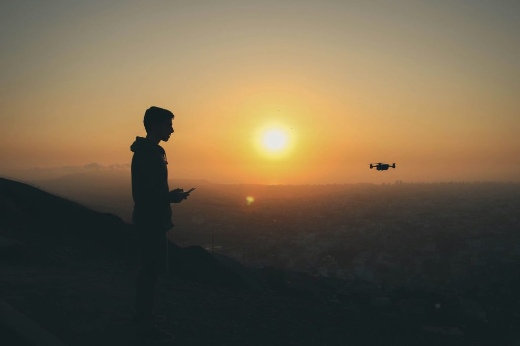 Person controlling drone while watching sunset.