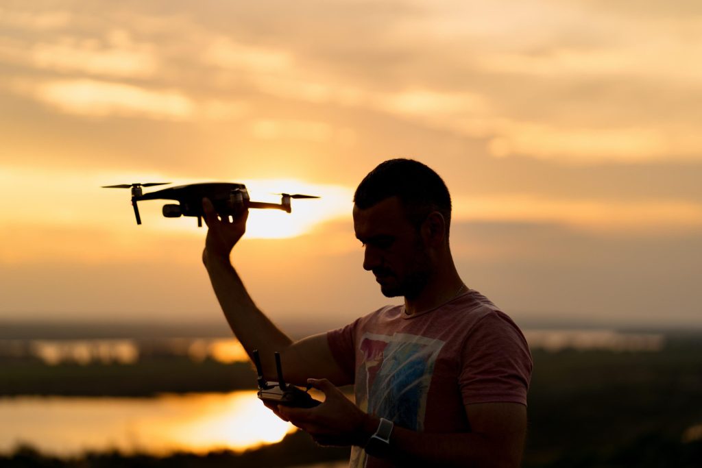 Man raising drone while controlling it.