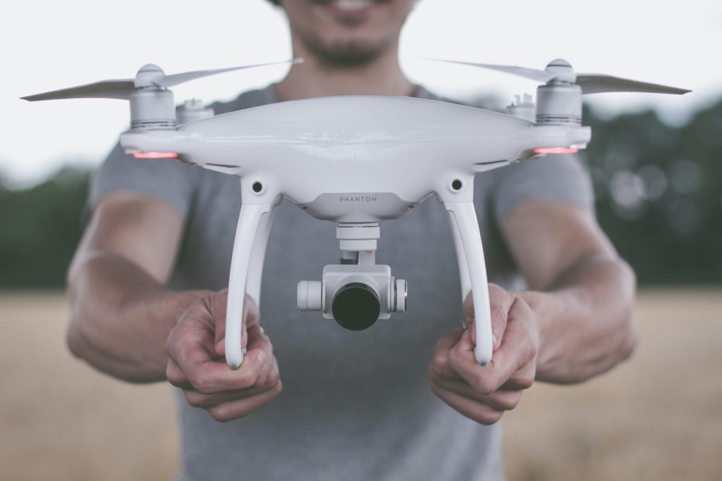 Holding a drone, smiling in a field.
