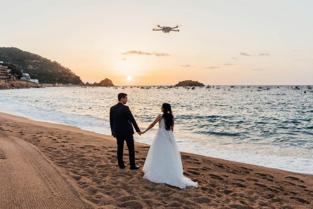 Wedding couple on beach with drone overhead.