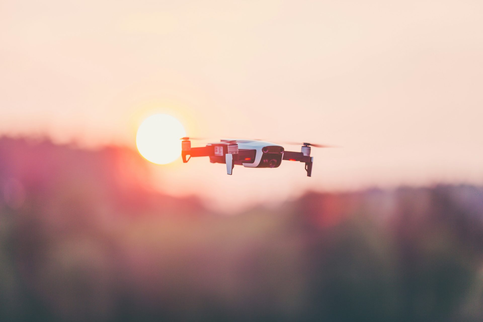Small drone flying with sunset backdrop.