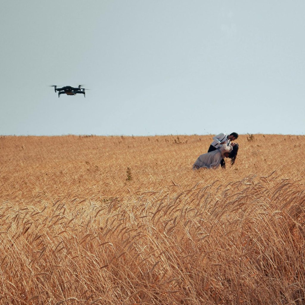 Couple embracing in a field, drone flying.